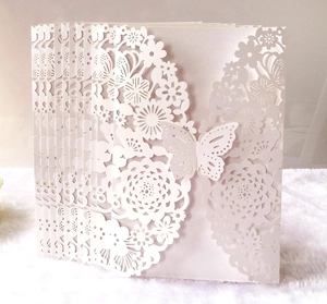 Detail of laser-cut wedding invitation featuring intricate white butterfly and floral patterns