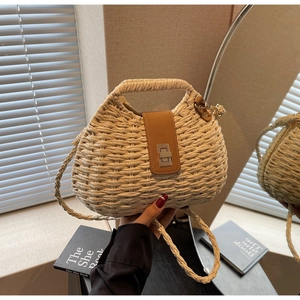 Detail of hand-woven straw crossbody bag featuring brown leather buckle and metal twist lock