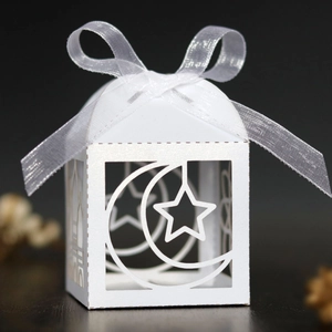 Close-up of white cutout candy box with ribbon bow featuring moon and star patterns