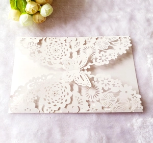 Detail of white laser-cut invitation card with intricate butterfly and floral patterns