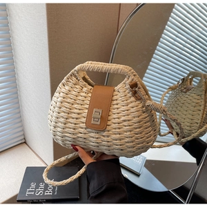 Detailed view of woven straw bag featuring brown leather flap and metal turn-lock closure
