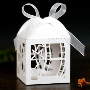 Close-up of white laser-cut film theme candy box with a delicate star pattern and white ribbon