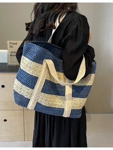 Large striped straw tote bag with canvas straps shown on model in a cozy indoor setting