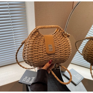 Detail of hand-woven straw crossbody bag with brown leather clasp and twist-lock hardware