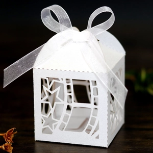 Detailed laser-cut white favor box with star patterns and organza ribbon bow