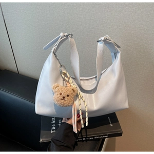 Detail of hobo shoulder bag in soft grey leather with plush bear pendant and woven charm