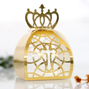 Close-up of laser-cut gold crown favor box with intricate hollow cross patterns