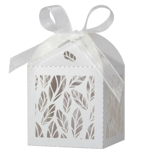 Detail of white laser-cut leaf patterns on wedding favor box with a silk ribbon bow
