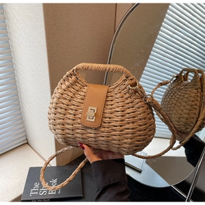 Detail of hand-woven straw crossbody bag featuring brown leather flap and gold twist lock