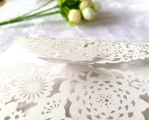 Detail of white laser-cut wedding invitation featuring a 3D butterfly design