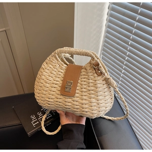Detailed view of beige woven straw bag with brown leather flap and golden twist lock
