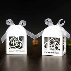 Detail of laser-cut moon and star patterns on elegant white Ramadan gift box with ribbon