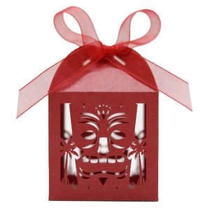 Detail of red laser-cut candy box featuring tribal mask and palm tree patterns