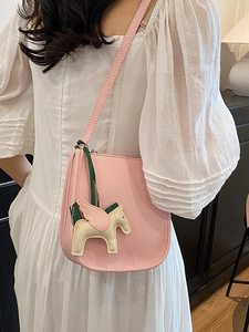 Pink lychee leather saddle bag with a pegasus charm shown from a side-view on a person