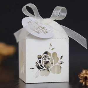 Detail view of laser-cut rose patterns on white pearlescent paper wedding gift box