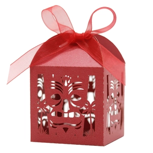 Close-up of laser-cut gift box with red ribbon and tropical tiki mask pattern