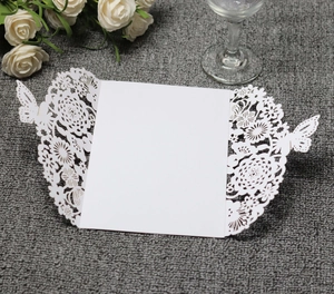 Macro shot of white laser cut invitation card with floral and butterfly hollow designs