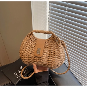 Detail of woven straw handbag featuring a semi-circle design with leather flap and metal lock