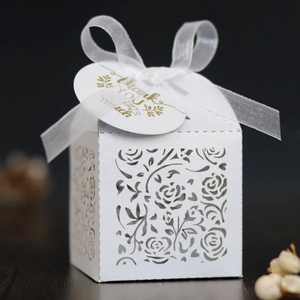 Macro shot of laser-cut rose hollow favor box with white organza ribbon and gift tag
