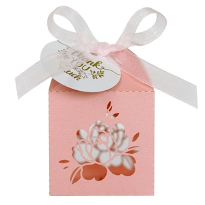 Close-up of pink laser-cut floral candy box with white silk ribbon and thank you tag