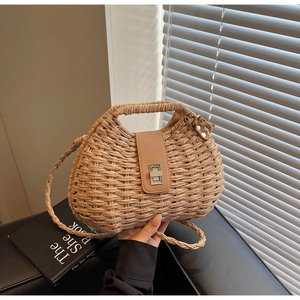 Close-up of the vintage straw woven bag featuring a brown leather lid and silver metal clasp