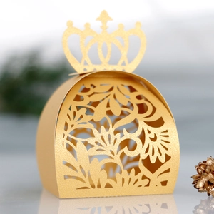 Détail de la boîte à bonbons de mariage dorée avec couronne et motifs découpés au laser