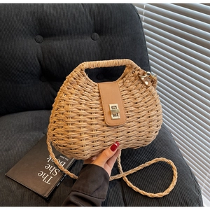 Detail of woven straw bag featuring brown leather flap and golden twist lock