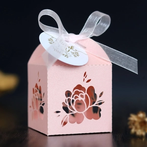 Detail of pink laser-cut wedding favor box with pearl finish, white ribbon and thank you tag