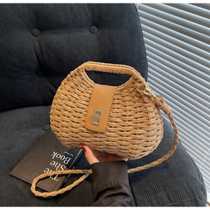 Detailed view of woven straw bag texture with leather flap and silver twist lock closure