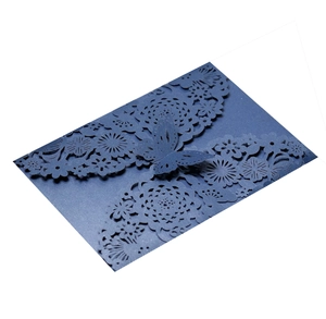 Detail of dark blue laser-cut wedding invitation with intricate butterfly and floral patterns