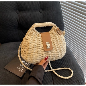 Detail of handwoven beige straw bag featuring a brown leather flap and metal turn-lock