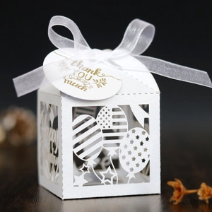 Close-up of white laser-cut birthday gift box with ribbon and gold thank you tag