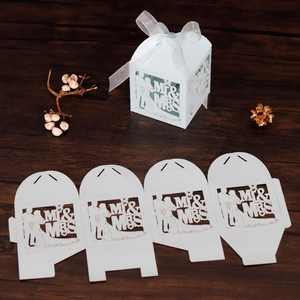Macro detail of laser-cut light blue wedding favor box with Mr & Mrs silhouette and ribbon