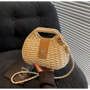 Macro detail of hand-woven straw crossbody bag featuring brown leather strap and metal buckle