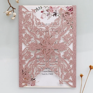 Detail of pink glitter laser-cut wedding invitation with hollow floral patterns
