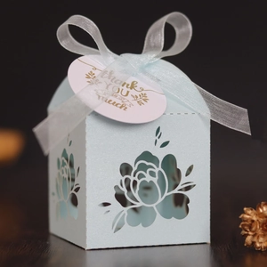 Macro shot of light blue laser cut floral candy box with white organza ribbon and gift tag