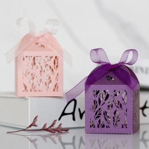 Detail of laser-cut leaf pattern gift boxes with elegant ribbon bows for weddings