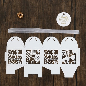 Flat lay of laser-cut white cardstock gift box with Happy Birthday text and silver ribbon