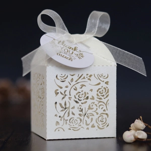 Detail of laser-cut rose hollow favor box in pearl white with thank you tag and ribbon