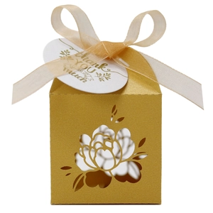 Close-up of golden laser-cut floral favor box with organza ribbon and thank you tag