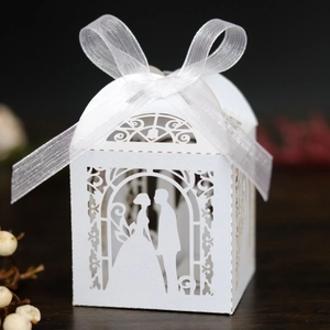 Close-up of laser-cut wedding favor box with bride and groom design and white ribbon