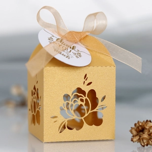 Macro view of laser-cut floral pattern on golden glitter wedding gift candy box