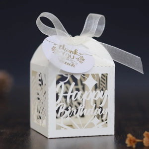 Detail of white laser-cut Happy Birthday gift box with ribbon and gold foil tag