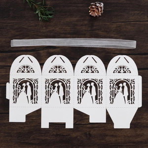 Flat lay of laser-cut wedding favor box featuring bride and groom silhouette and ribbon
