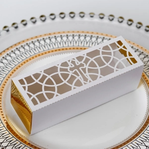 Detailed laser cut white gift box with gold foil lining and cross pattern on a plate