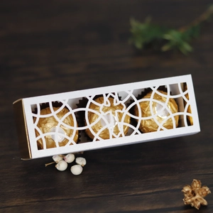 White laser-cut wedding favor box with gold lining and hollow ring pattern for chocolates