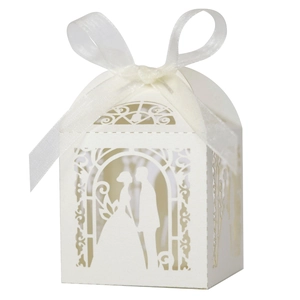 Macro view of white laser-cut wedding favor box with silhouette and satin bow detail