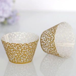 Close-up of laser-cut gold cupcake wrappers with intricate vine pattern and glitter finish