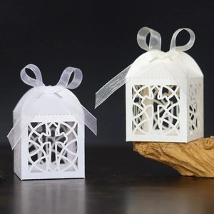 White laser-cut cross favor boxes with elegant ribbons for weddings and baptisms