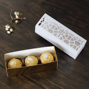 Macro view of white laser-cut gift box with hollow cross design and gold chocolate tray